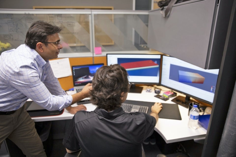 Photograph of Hasan Ozer working with a graduate student at a computer. They are discussing the pavement model that was created using specific software.